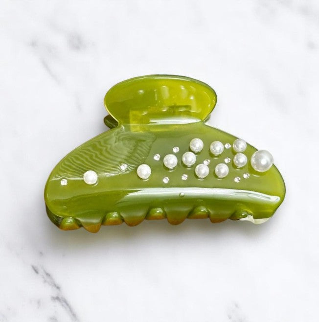 Green hair clip with pearl decoration on marble background