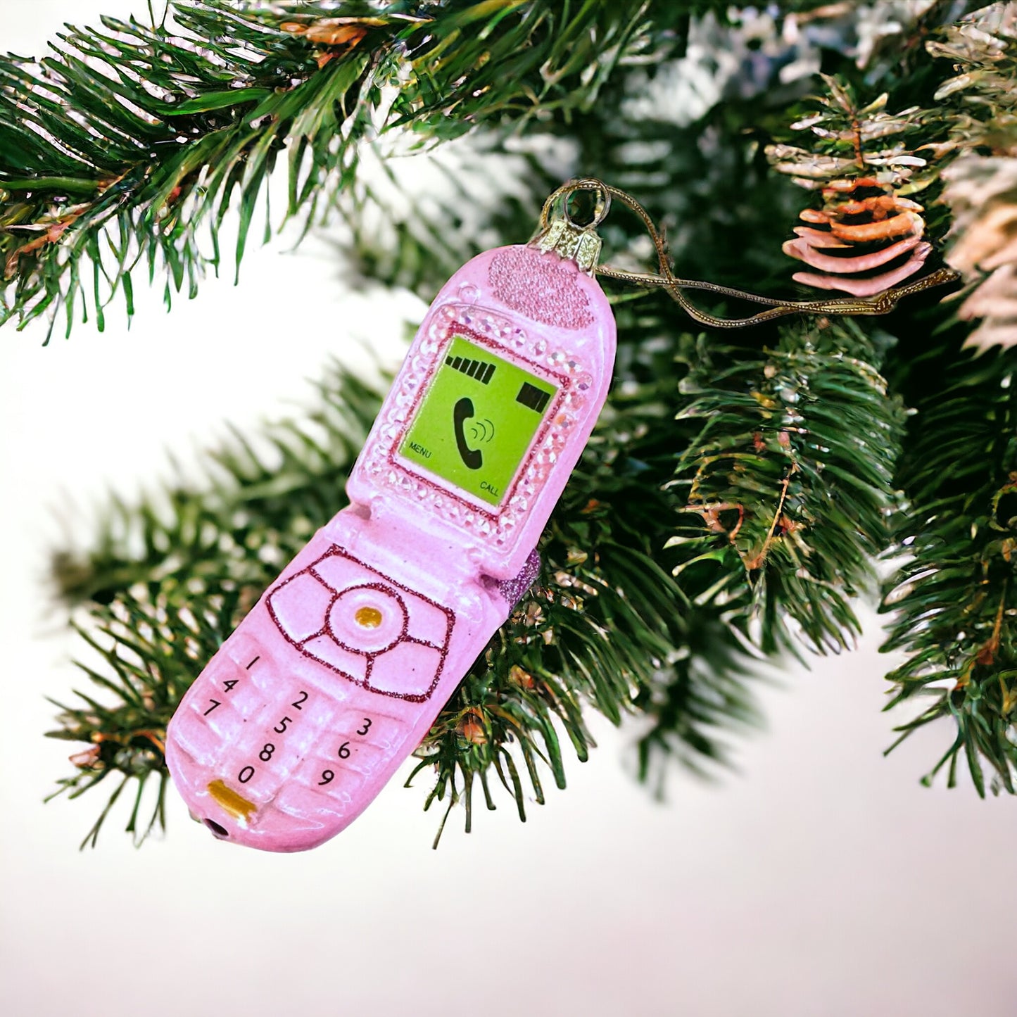 Glittery pink ornament shaped like a flip phone, bringing retro flair to holiday decorations.