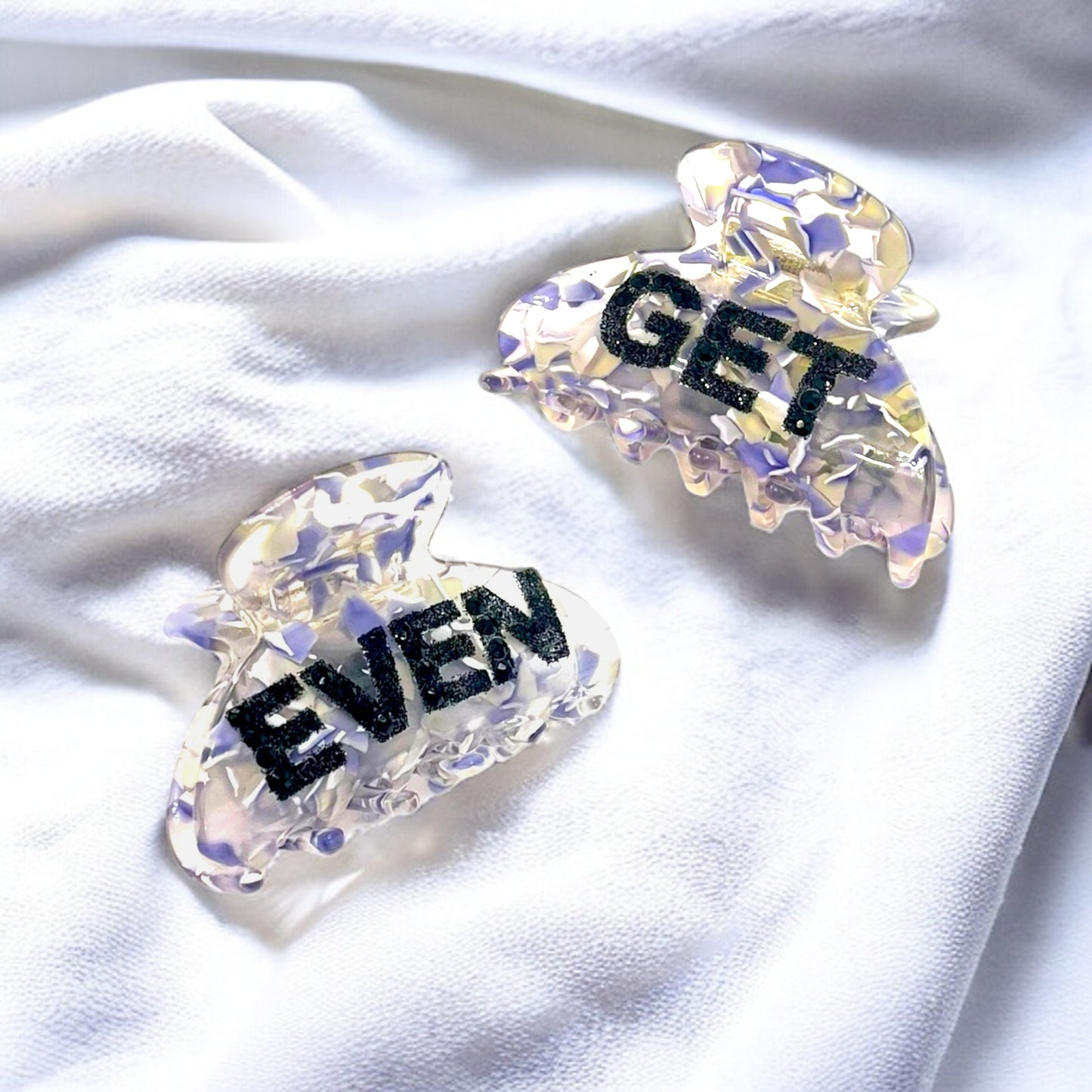 Playful "Get Even" glitter hair clip with iridescent design, offering a secure hold for thick hair.