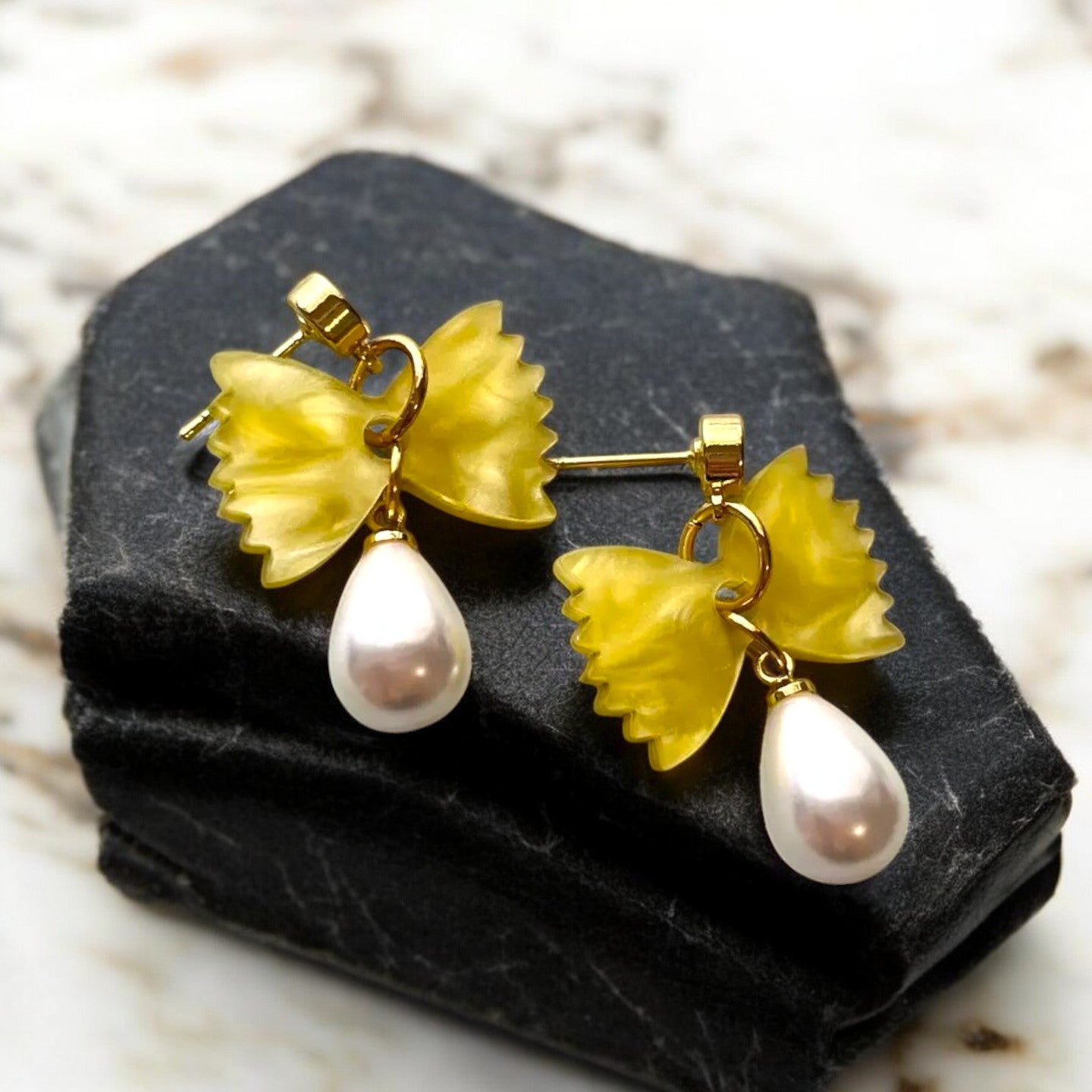 Chic yellow pasta bowtie earrings with pearl drops.