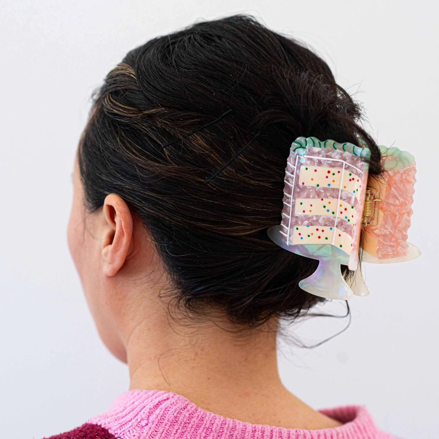 Woman wearing a decorative cake hair clip.