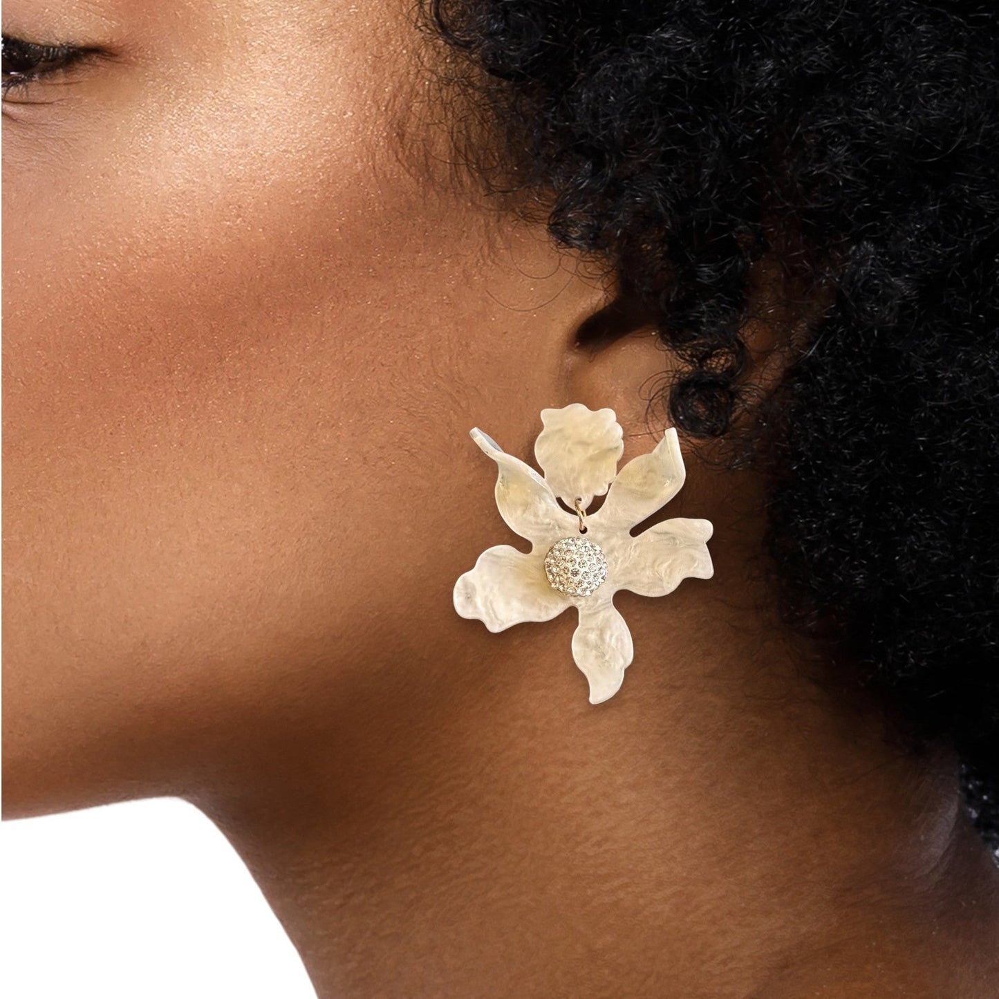 Textured gold earrings with dangling floral charms on a model.