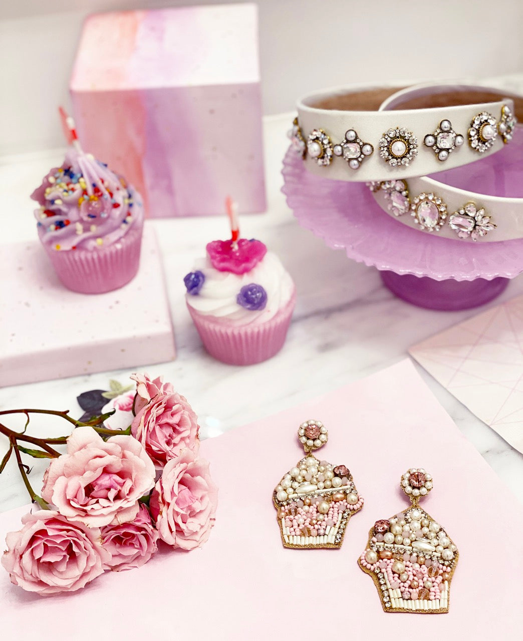 Trendy cupcake earrings adorned with pink and white beads, showcasing a "Carrots vs. Karats" patch on the back.