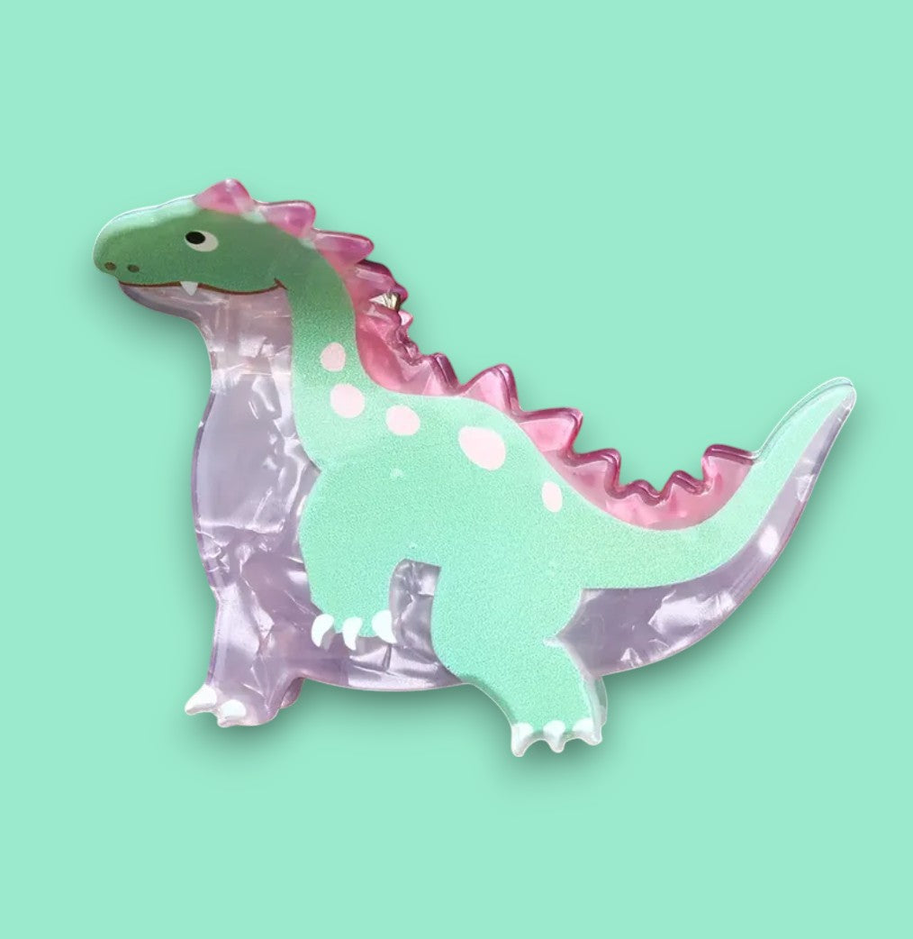 Pastel dinosaur hair clip on a green background