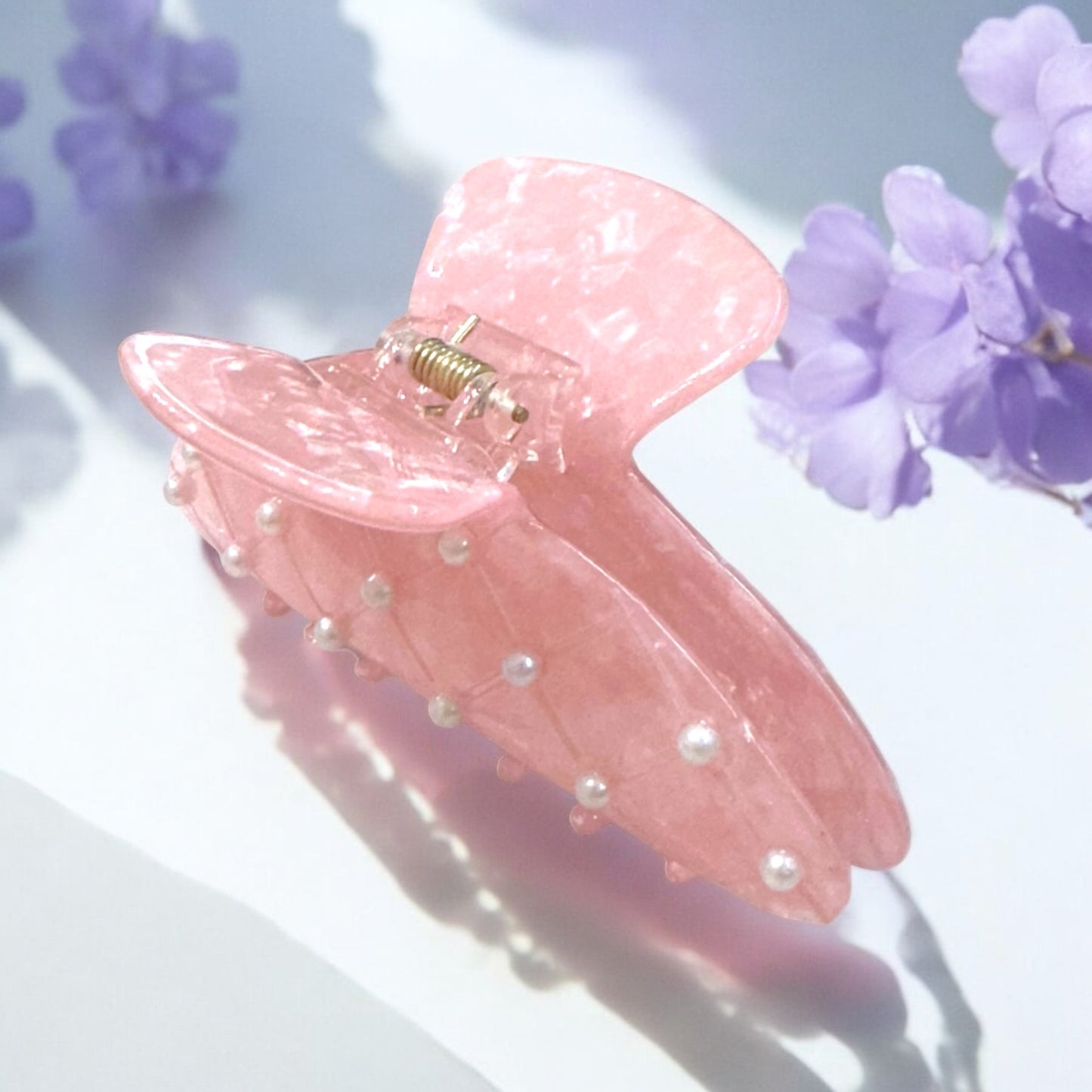 Close-up of a pink pearl hair clip, ideal for stylish and secure hairdos.