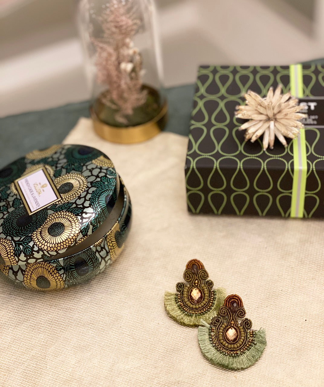 Artistic green earrings with Buddha patches and fringe details.