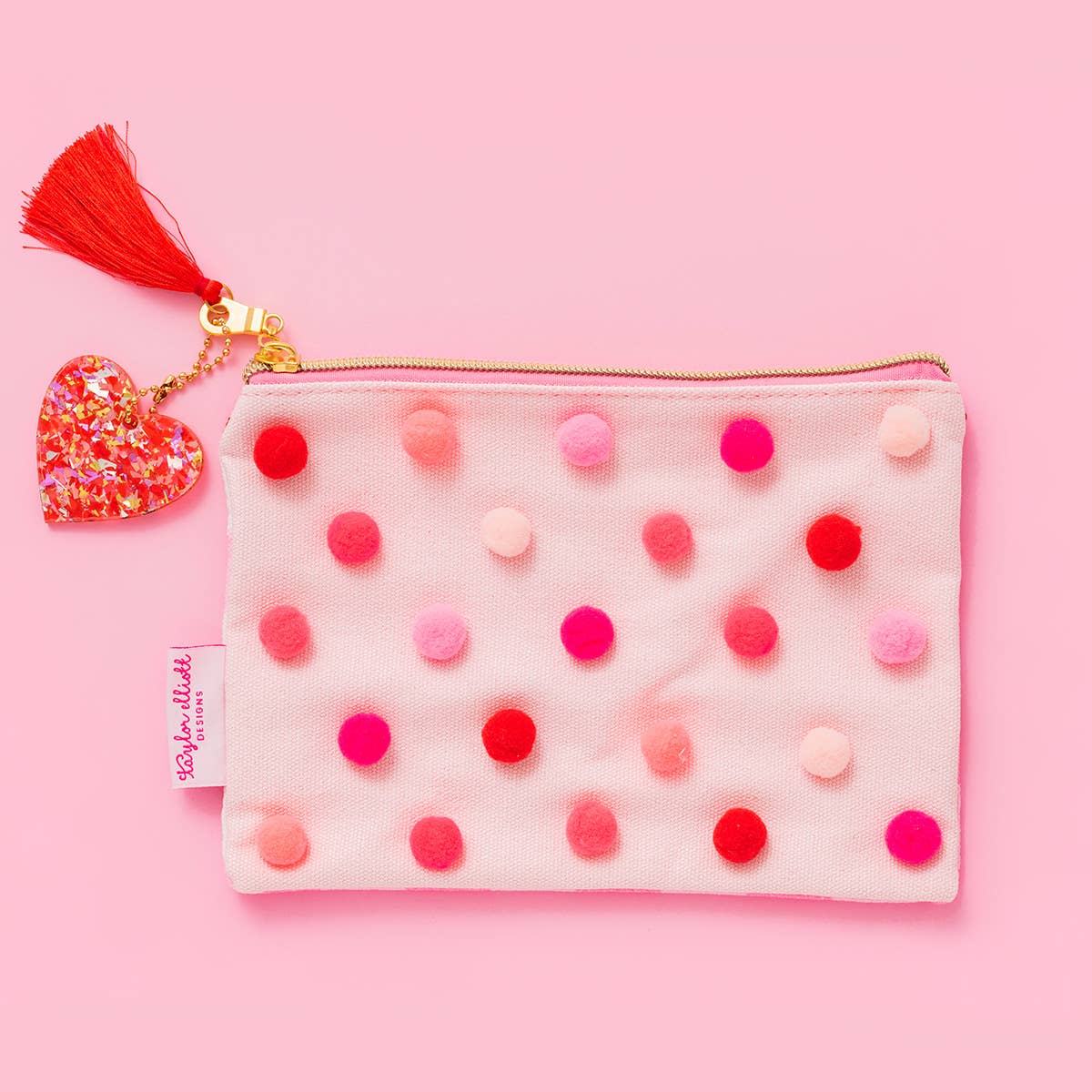 Colorful pom pom pouch on a pink background.