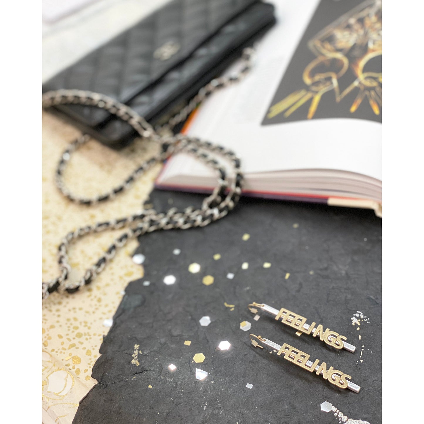 Long lightweight drop earrings featuring the word FEELINGS in gold tone