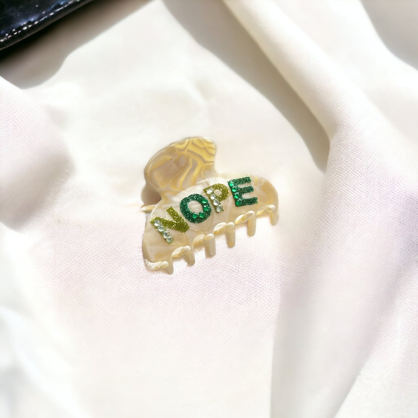 Small acetate hair clip with bold "NOPE" rhinestone lettering, perfect for adding a fun touch to any hairstyle.