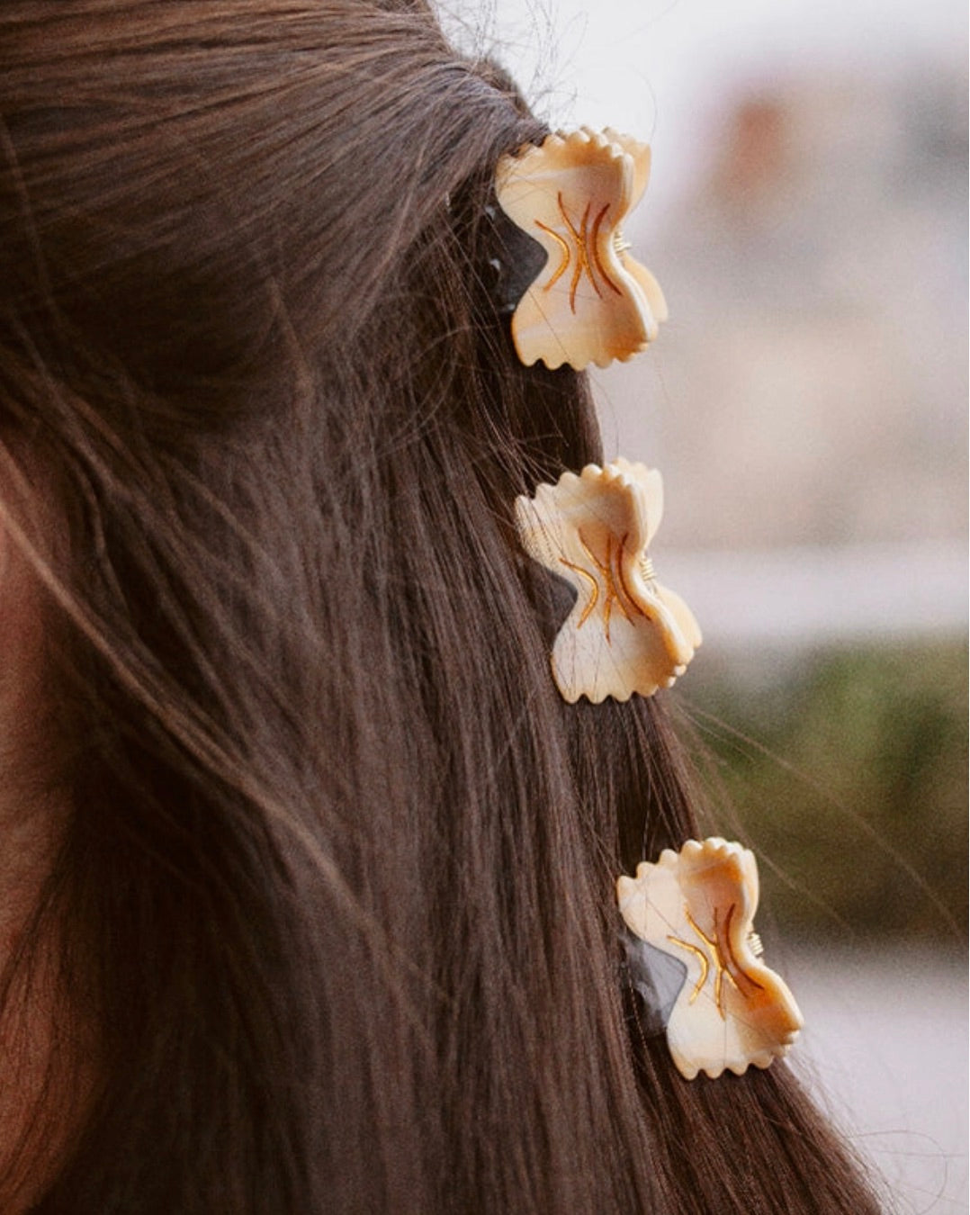 Bowtie hair clips clipped in a row on straight brown hair, showcasing the design.