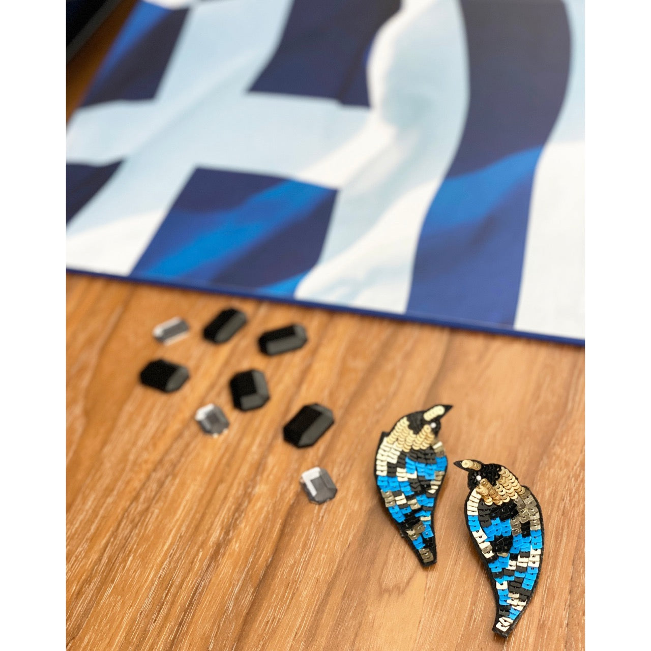 Handmade sequin bird earrings with stitched “Whatevs” detail in black, blue, and gold tones.