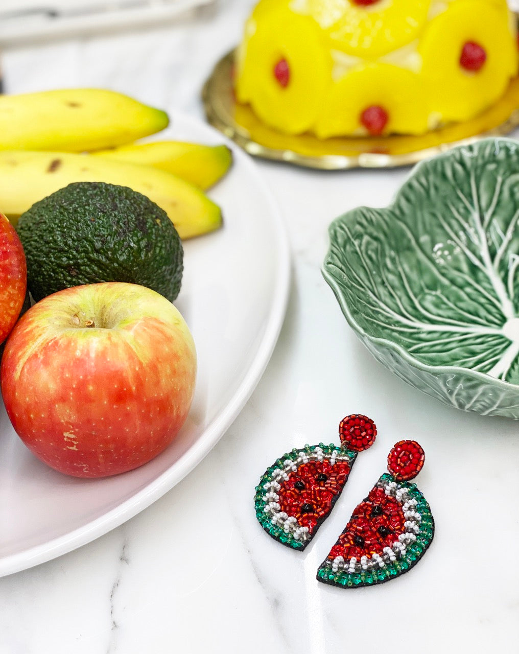 Whimsical earrings combining sparkling beaded watermelon halves with embroidered drink and heart-eyes emoji details on black felt tops.