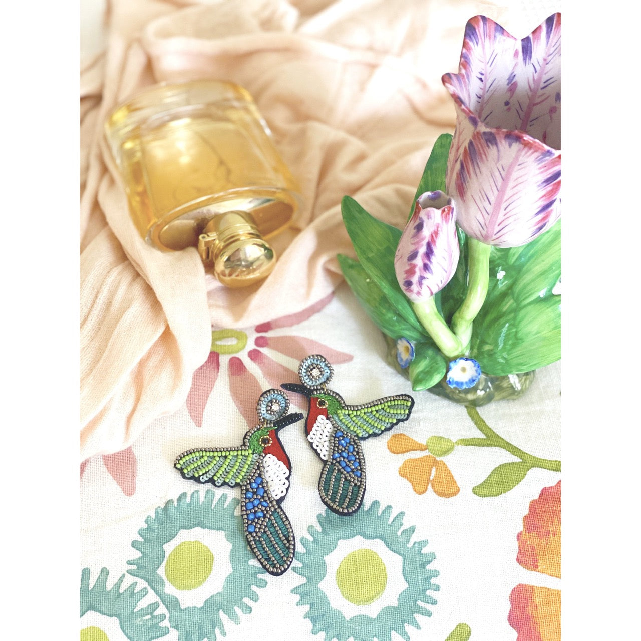 Vibrant beaded hummingbird earrings, showcasing intricate craftsmanship and a meaningful "Peace and Love" patch design.