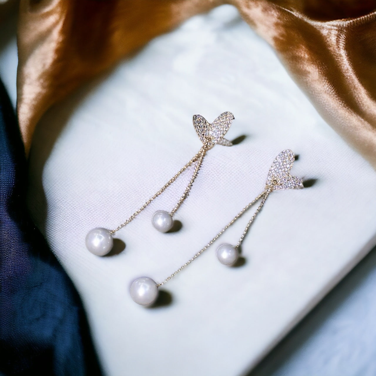 Gold heart earrings with long dangle pearls, a sophisticated and elegant accessory.