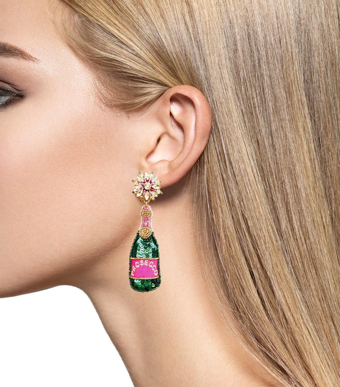 Playful and sparkly earrings shaped like prosecco bottles with green sequins, a pink label, floral studs, and "Carpe Diem" embroidered on the back.