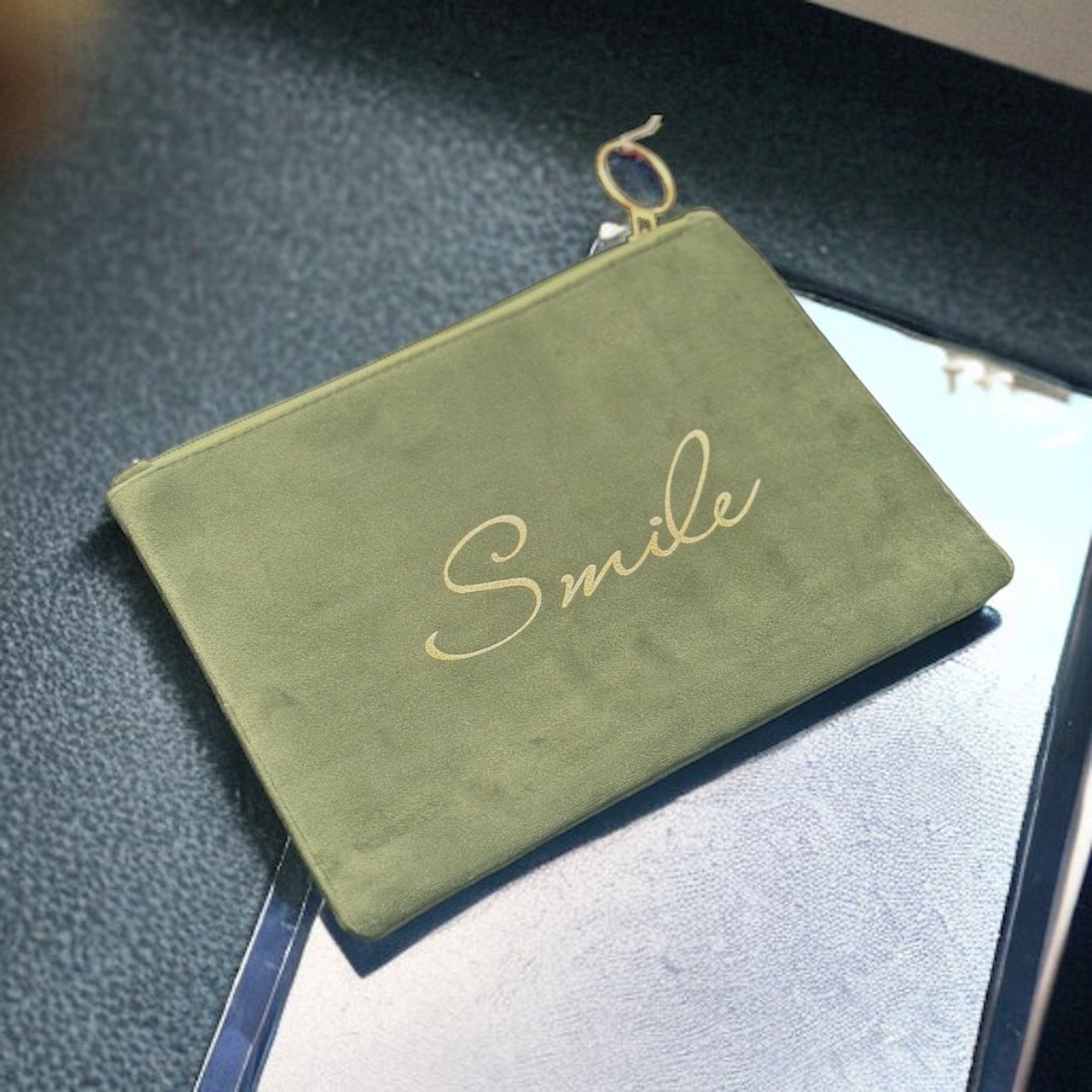 A small, handmade yellow suede pouch with a big smile embroidered on the front.