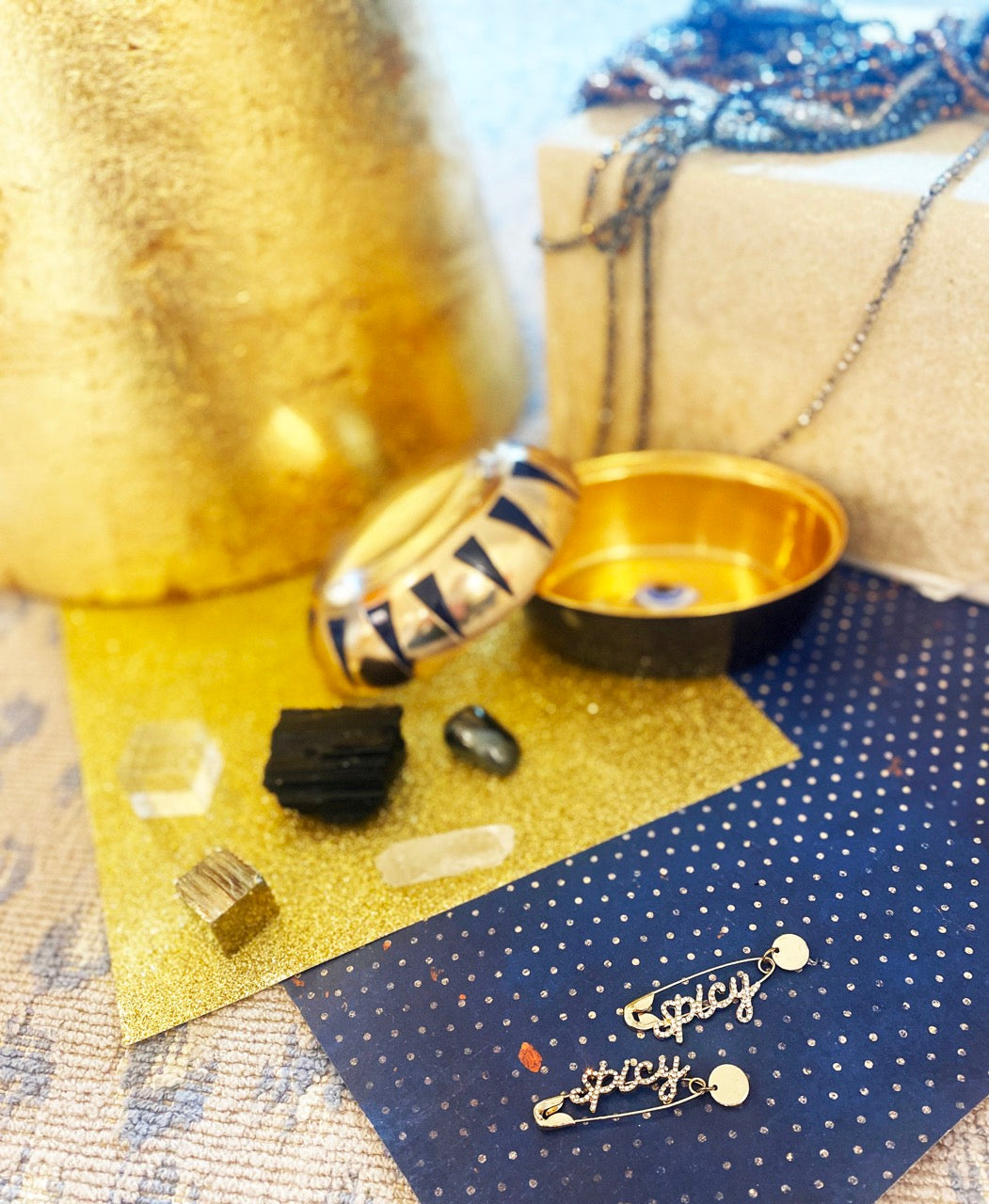 Gold dangle earrings shaped like safety pins with SPICY in rhinestones