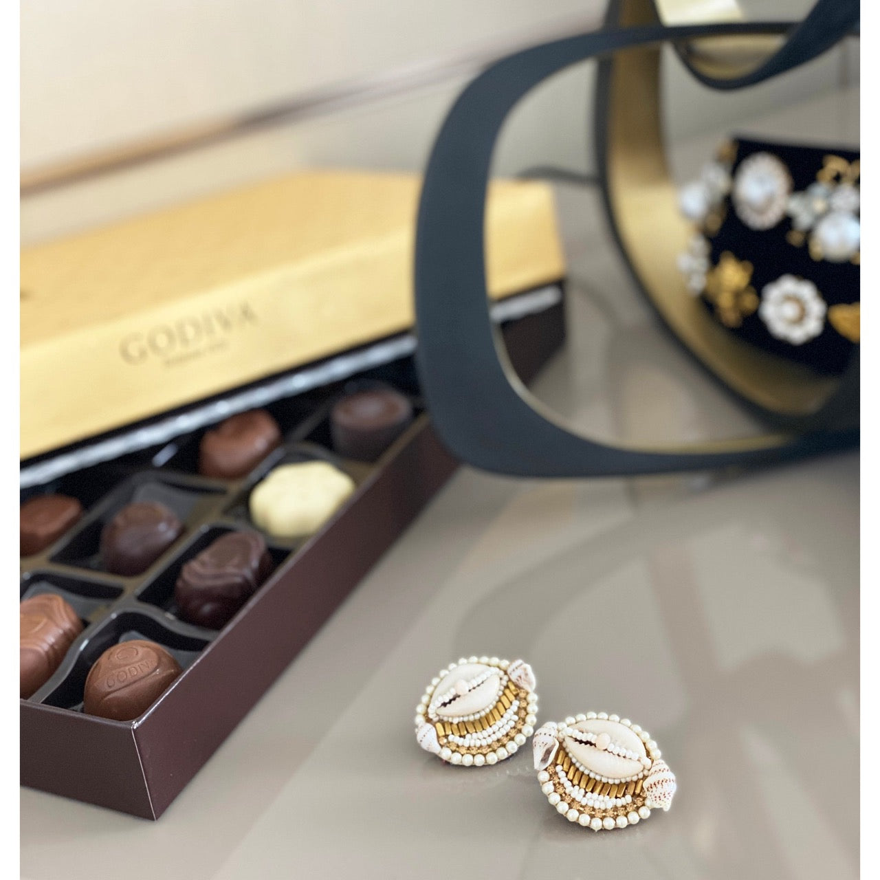 Stylish shell earrings with pearly white and gold beadwork, accented with a unique patch design.