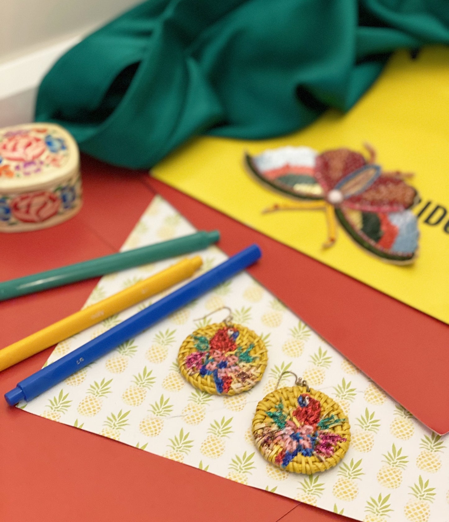 Chic parrot earrings crafted from emerald green enamel and suspended on a delicate gold hoop, offering a touch of tropical elegance and sophistication.