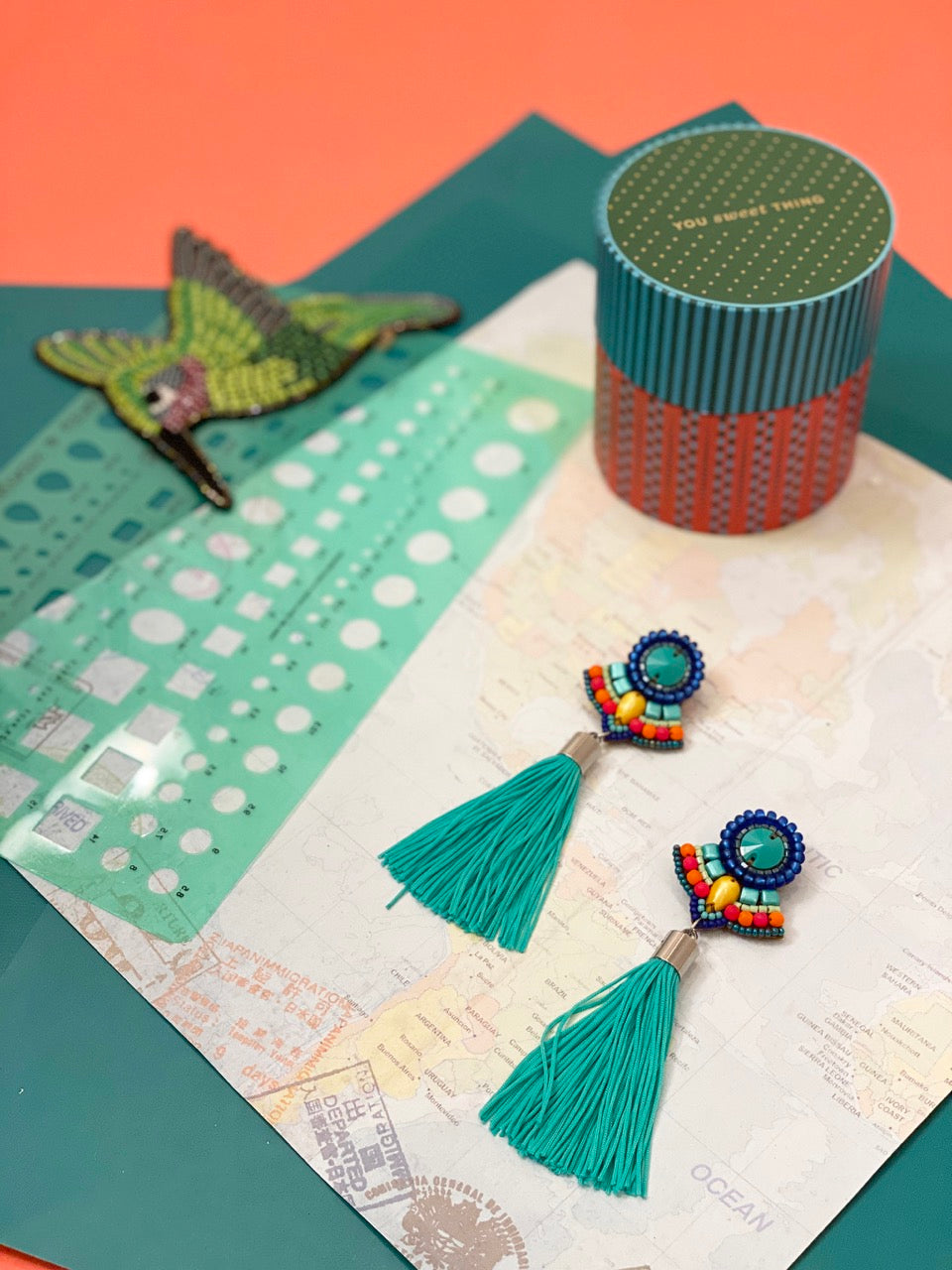 Whimsical tassel earrings with teal fringe, vibrant bead designs, and friendship-themed broken-heart charms.