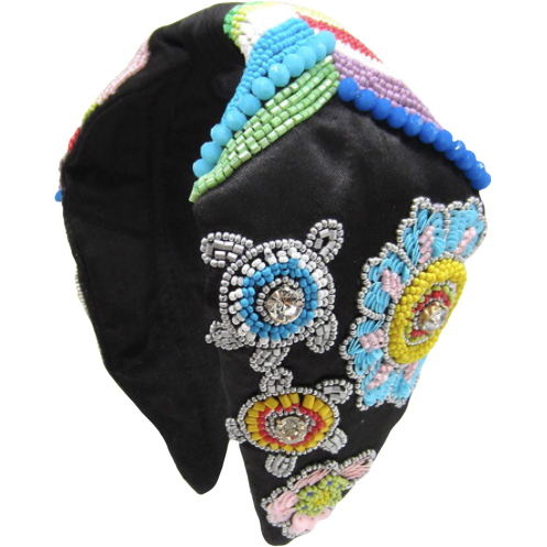 Close up of a handmade headband decorated with large green beads, gold wire, and clear tortoise shell hair clips.