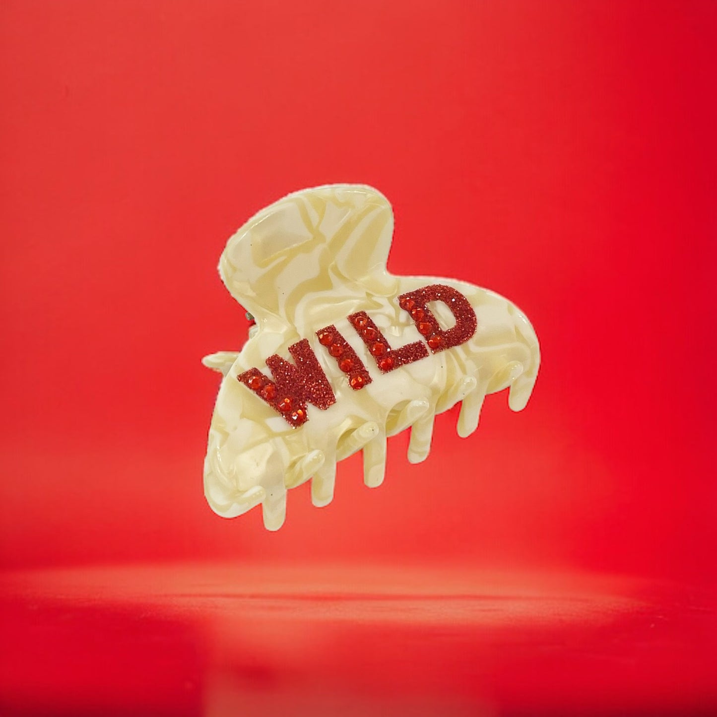 Cream hair clip with the bold text WILD in glittery red.