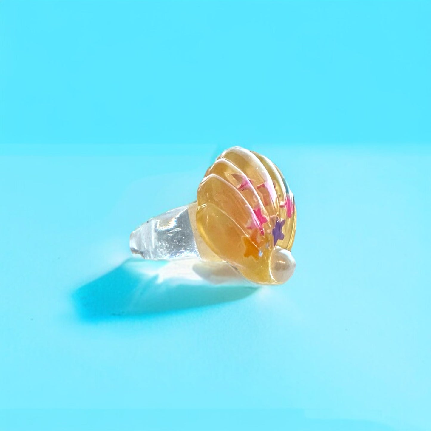 Vibrant yellow shell ring with a lustrous pearl, offering a unique and stylish accessory for any occasion.