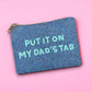 Glittery beaded zipper pouch with playful “Put It On My Dad’s Tab” text, laid flat against a pink backdrop.