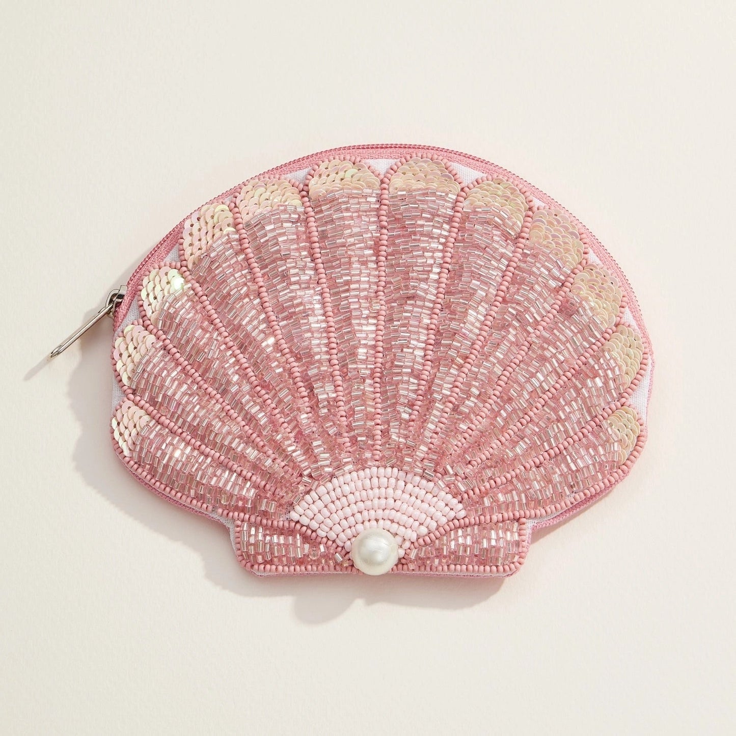 Blush and gold sequin seashell pouch with pearl accent on white background