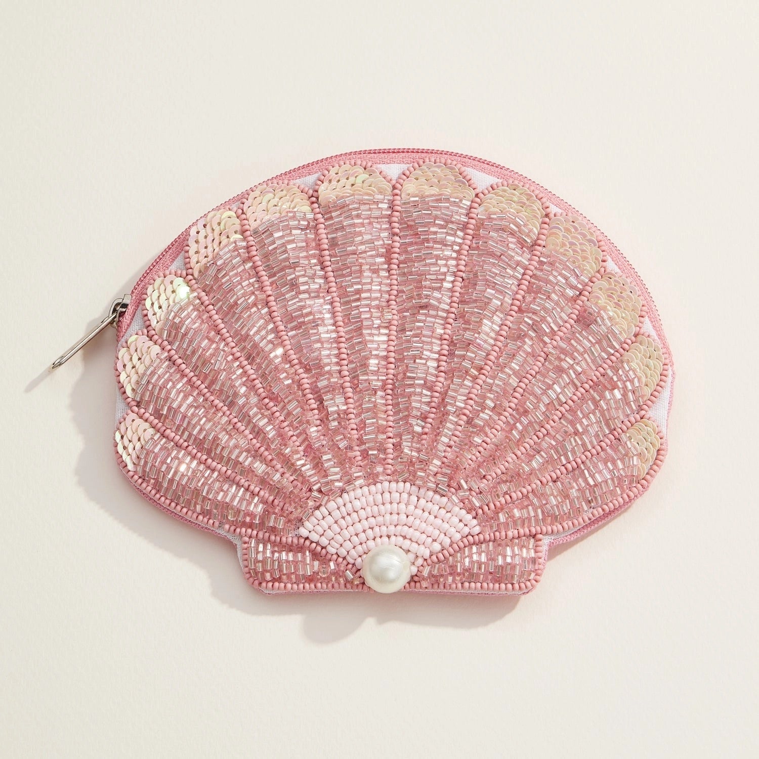 Blush and gold sequin seashell pouch with pearl accent on white background