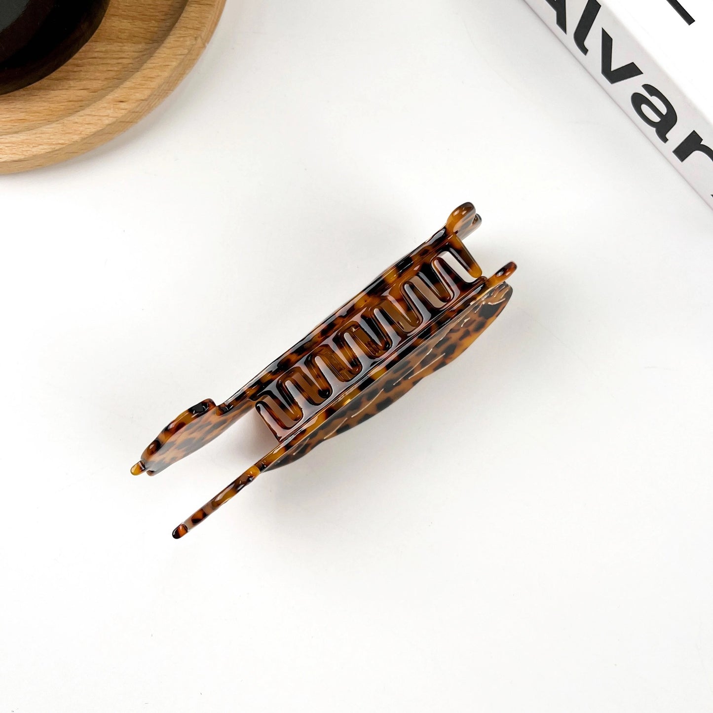 Minimalist top-down image of tortoise clip showing prong detail and glossy finish.
