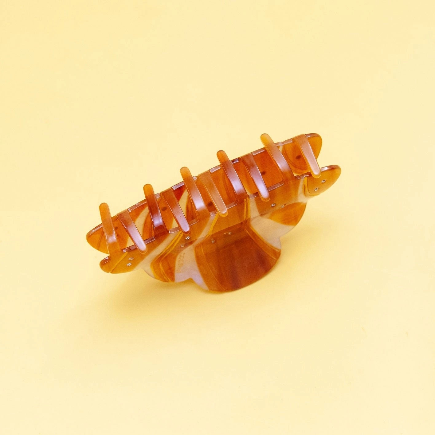 Back view of croissant-shaped amber and ivory claw clip with open prongs and sparkling accents.