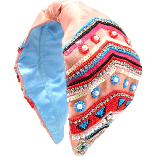 Vibrant Dreamweaver headband in coral with blue tones and a knot design.