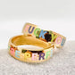 Stack of two gold rings with rainbow enamel lettering, one saying "FUCK YOU" and the other "YOU'RE PERFECT", cheeky and colorful jewelry set
