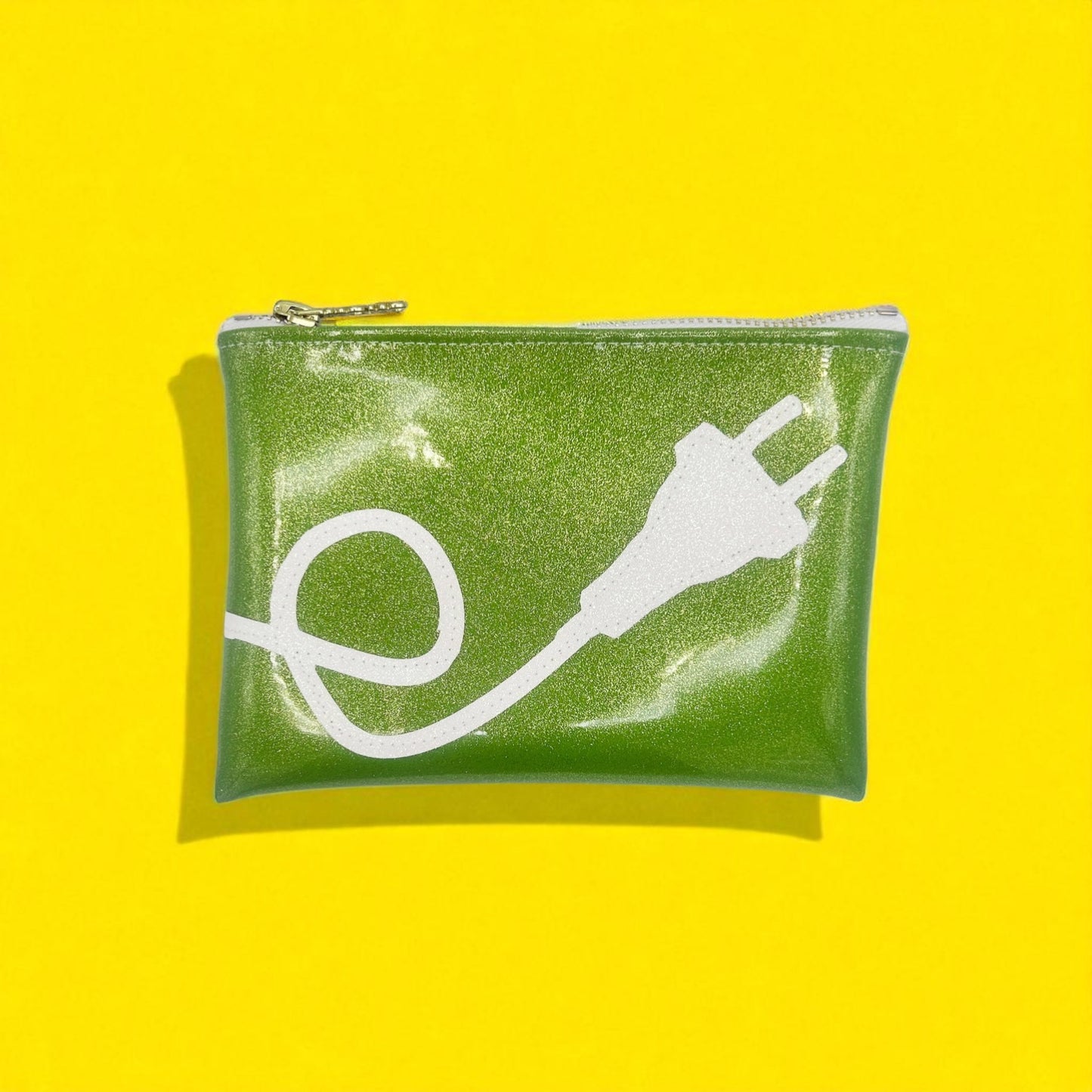 Glittery green tech pouch with white power plug design, styled on vibrant yellow background