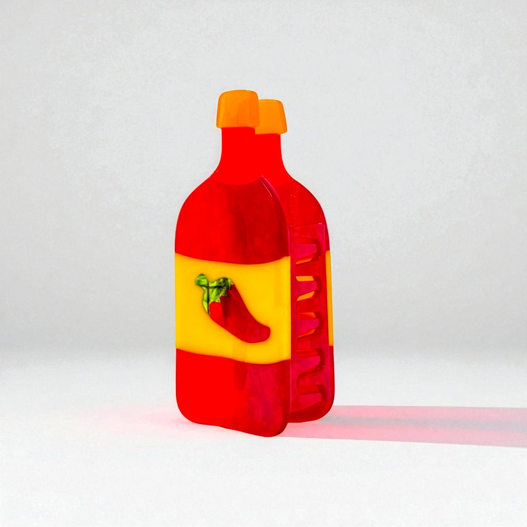 Full front view of a novelty hot sauce claw clip in red, yellow, and orange acrylic with pepper graphic.