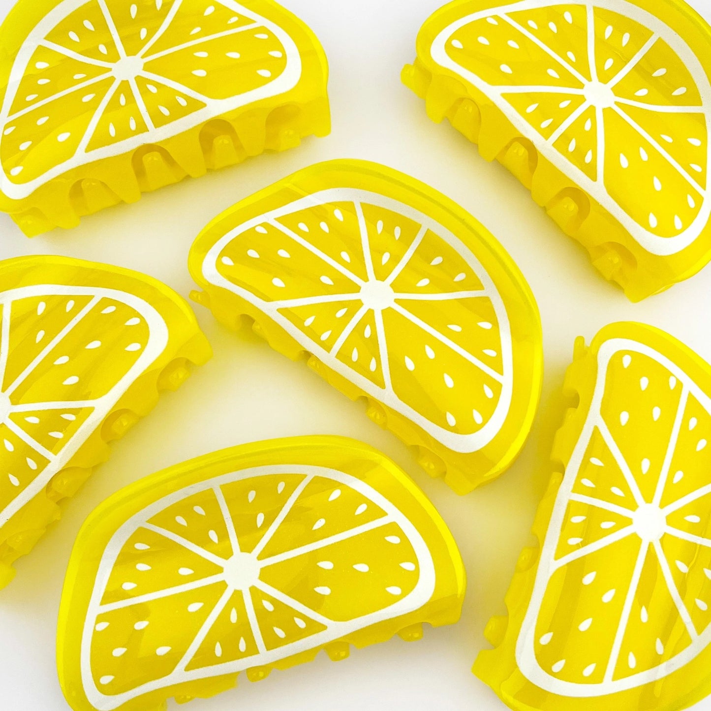 A group of lemon claw clips including open and closed views, styled on white with yellow flowers.