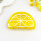 Yellow acrylic lemon slice hair clip styled on white with delicate yellow flowers.