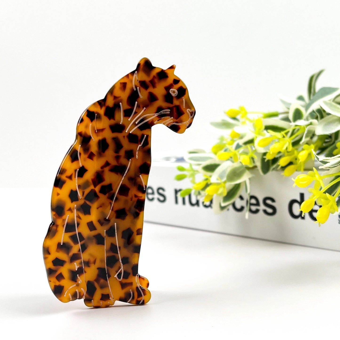 Large tortoise claw clip with curved design standing upright beside a modern art book.