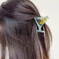 Martini glass claw clip holding half-up hairstyle in dark brown hair.