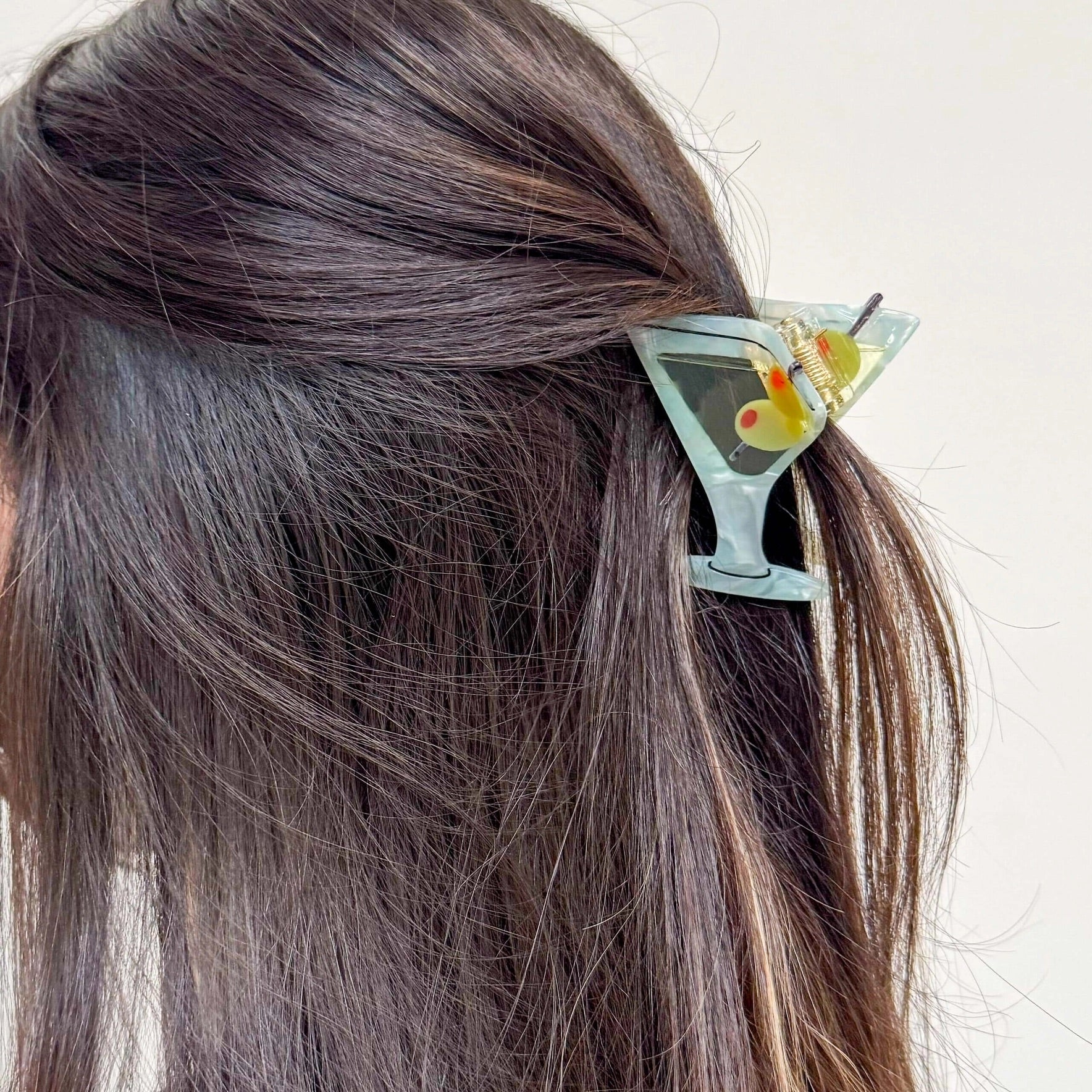 Martini glass claw clip holding half-up hairstyle in dark brown hair.