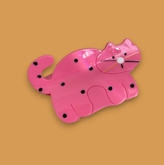 Pink cat hair clip with black dots.