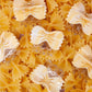 Multiple cream-colored bowtie pasta hair clips displayed on real bowtie pasta background.