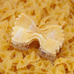 Bowtie pasta-shaped hair claw clip designed to look like farfalle, resting on a bed of real uncooked pasta.