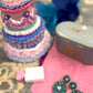Aqua floral statement earrings displayed on a pink surface with a pastel frosted faux cake and teal vintage tin.