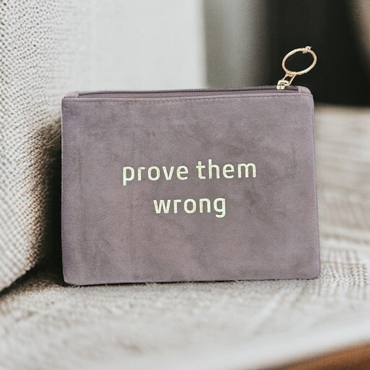 A chic and versatile suede pouch adorned with the empowering slogan "Prove Them Wrong" for carrying essential accessories.