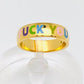 Gold statement ring with colorful rainbow enamel letters spelling "FUCK YOU", bold and edgy jewelry design