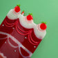 Top view of red cake hair clip with strawberry decorations and white icing details”