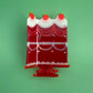 Full view of the red cake slice hair clip resembling a dessert on a stand