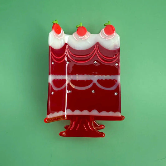 Full view of the red cake slice hair clip resembling a dessert on a stand